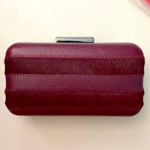 Burgundy haircalf/leather striped minaudiere. He metal trim and strap.